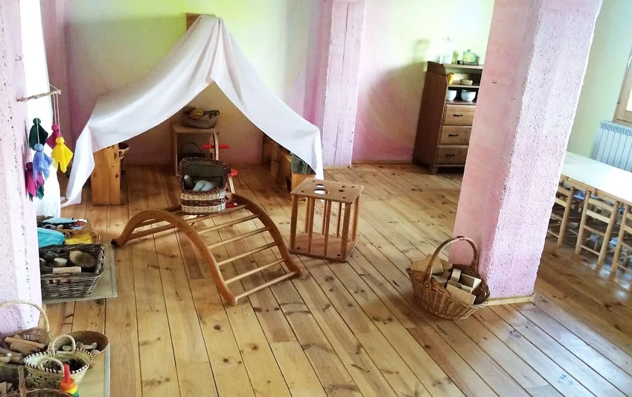 La sala de joc de Brolls, amb una cabana de tela, una escala d'equilibri de fusta i cistells